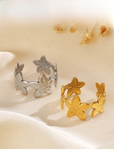Dettaglio degli anelli a forma di fiore regolabili in oro e argento su tessuto di seta