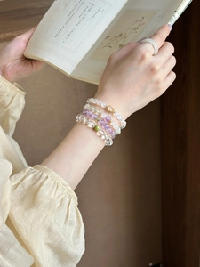 Detail of stacked amethyst and moonstone beaded bracelets on wrist with a minimalist ring
