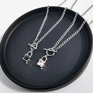Close-up of silver toggle clasp necklaces with black and pink square crystal lock pendants