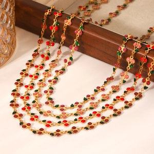 Detail of gold cherry necklace with red and pink enamel pendants and green leaves