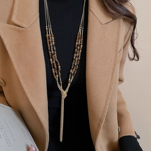 Close-up of golden tassel necklace with amber crystal beads on an elegant winter coat