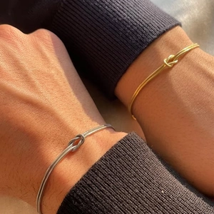 Close-up of minimalist S925 silver snake chain couple bracelets with knot detail
