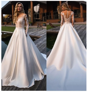 Detail of elegant lace embroidery bodice and long sleeves on a white satin wedding gown