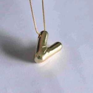 Detailed view of polished golden letter V pendant necklace with sleek mirror finish