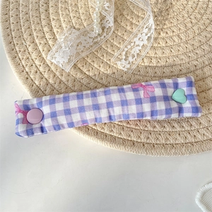 Close-up of purple plaid fabric cable organizer with cute bow and heart button detail