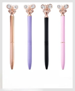 Detail of four butterfly-topped pens in rose gold, purple, black, and pink with crystals