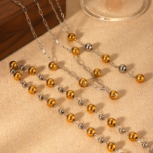 Close-up of mixed gold and silver bead chain necklace on a soft beige fabric background