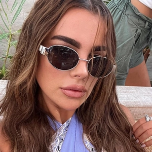 Close-up of a silver oval metal sunglasses on a fashion model with natural outdoor lighting
