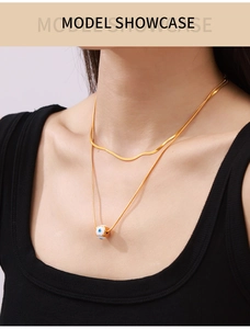Nahaufnahme der goldenen Schlangenkette im Layer-Look mit blauem Evil-Eye-Anhänger