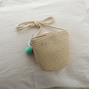 Detail of mini straw bucket bag with colorful pom-poms and woven cotton rope strap
