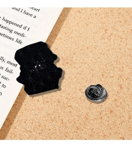 Detail of metal pin back with butterfly clasp on an open book over cork board