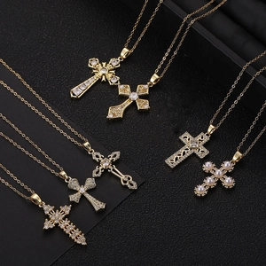 Golden cross necklace pendants set with cubic zirconia and pearls on grey texture