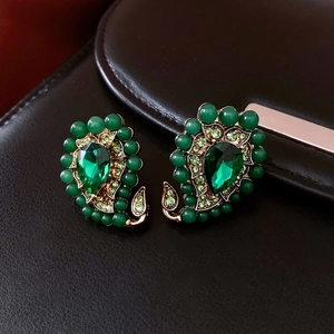 Détail de boucles d'oreilles vintage en goutte avec strass verts sur cuir