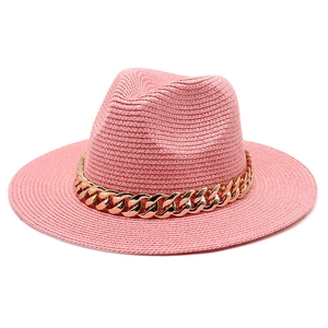 Close-up of pink woven straw fedora hat featuring a chunky gold chain link band detail