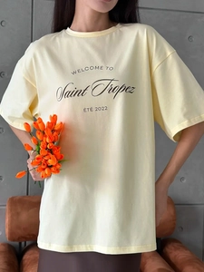 Detail of light yellow cotton T-shirt featuring minimalist black letter printing