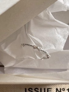 Detail view of a 925 sterling silver bow ring inside a beige gift box with white tissue