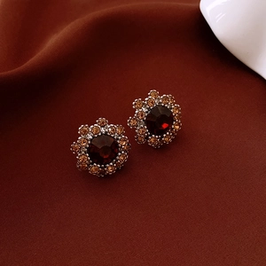 Macro shot of vintage flower earrings with ruby red center and amber halo crystals