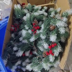 Close-up of artificial pine branches with red berries, pinecones, and frost for Christmas