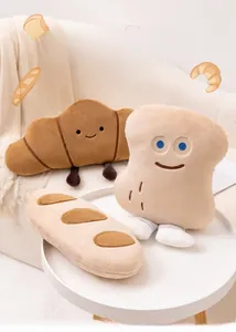 Détail des coussins en peluche en forme de pain, baguette et croissant, sur une table blanche