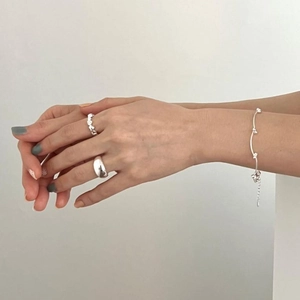 Close-up of 925 silver rings and star charm bracelet on model hand in white background
