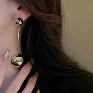 Close-up of long silver ball drop earrings worn by model for elegant style