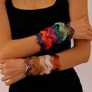 Close-up of vibrant wavy acrylic bangles with marble patterns layered on model's arms