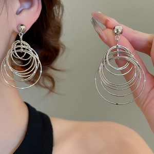 Detail of layered silver metallic hoop earrings showing multi-layered nested structure