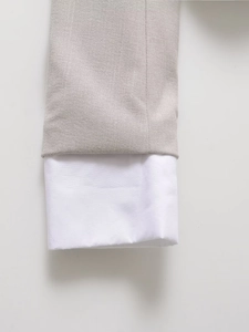 Detailed macro view showing light grey cuff texture with layered white shirt detail