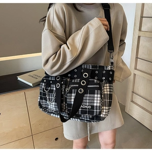 Detail of checkered crossbody bag with metal rivets, chain decor, and wide strap