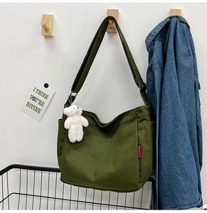 Detail of army green canvas crossbody bag featuring a cute white bear pendant on side