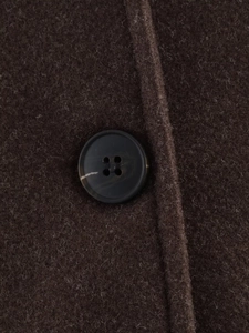Macro detail of dark brown wool coat fabric featuring a black four-hole button