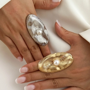 Detailed view of gold and silver textured metal rings with central white pearls