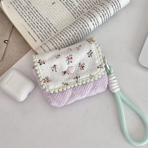Macro view of floral quilted fabric pouch with heart buckle and teal pom pom trim