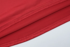 Close-up of double-needle stitching on the hem of a stylish red V-neck long-sleeve dress