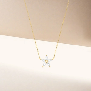 Macro shot of gold five-petal flower pendant with marquise-cut crystals on minimalist chain