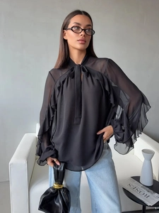 Detail of black chiffon blouse showing ruffled bell sleeves and elegant bow neck tie