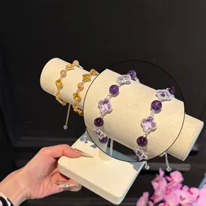 Détail de bracelets trèfles avec perles violettes et jaunes sur supports à bijoux