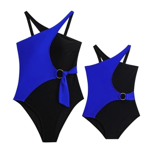 Detail of color-block swimsuit with gold metal ring and tie accent on the waist