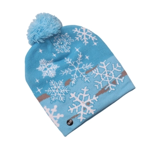 Detail of blue knitted Christmas hat with white snowflakes and LED power button