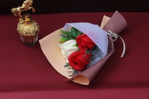 Detail showing artificial roses and baby breath wrapped in pink paper with ribbon