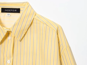 Dettaglio del colletto della camicia a righe gialle e bianche con etichetta taglia XS