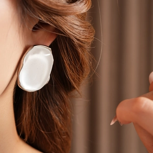 Close-up of minimalist silver-tone irregular oval resin earring on a model ear
