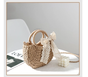 Close-up of handmade woven straw bag with delicate lace bow detail and textured finish