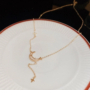 Gros plan du collier lune et étoile doré avec zircons posé sur un plateau en céramique