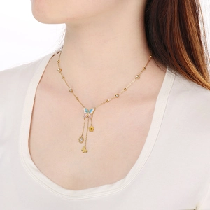 Close-up of gold butterfly tassel necklace with blue and pink enamel on woman's neck