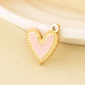 Macro view of pink enamel heart pendant with golden beaded edge and hanging loop