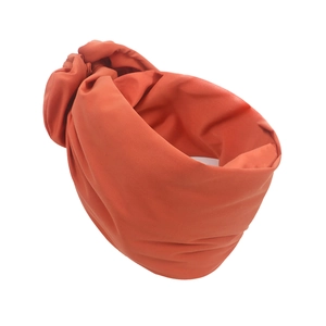 Detailansicht des orange-roten Strickstoffs und des zentralen Knotens der Turban-Mütze