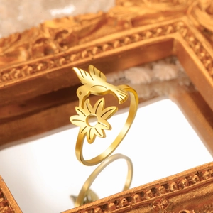 Detail view of 18K gold plated hummingbird and flower ring inside a vintage gold frame
