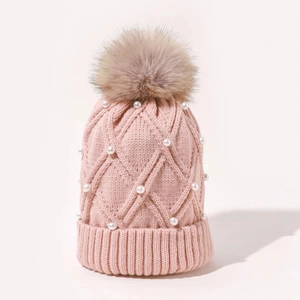 Pink knit beanie with rhombus pattern, white pearl accents and a fluffy pom-pom top