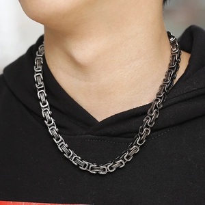 Close-up of men's chunky stainless steel Byzantine chain necklace on black hoodie